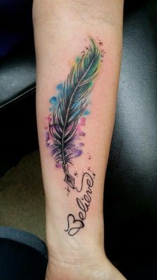 Tatouage plume turquoise et rose sur l'avant bras